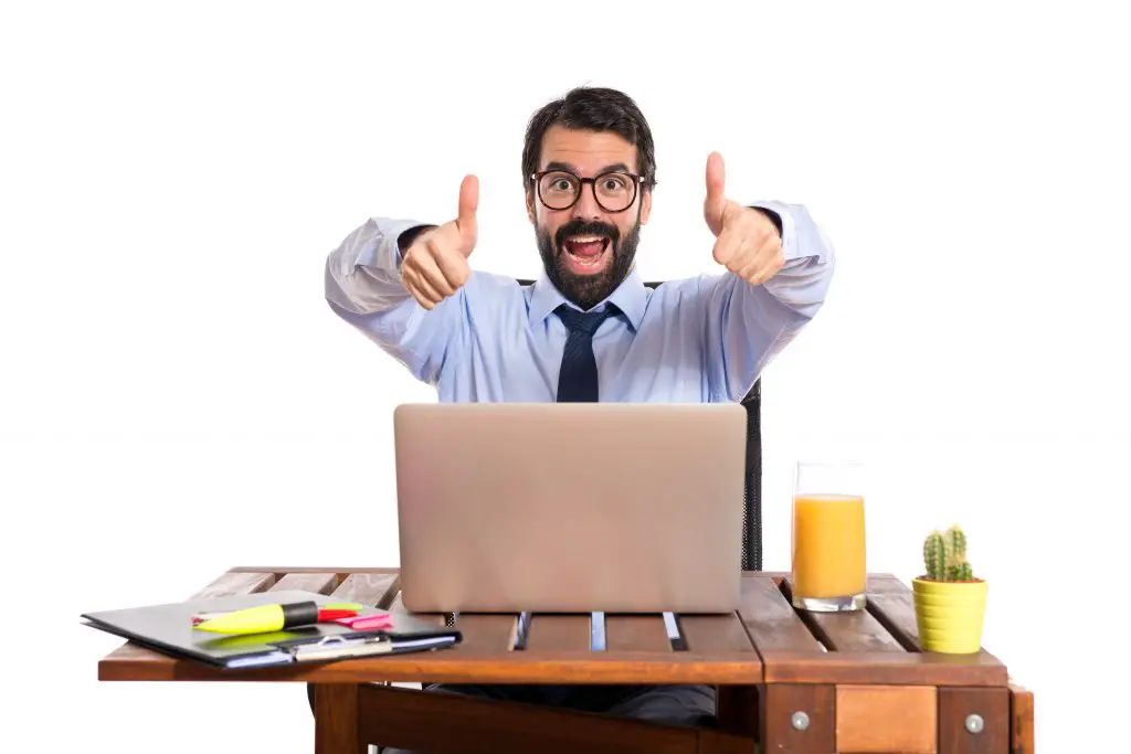 Businessman in his office with thumb up